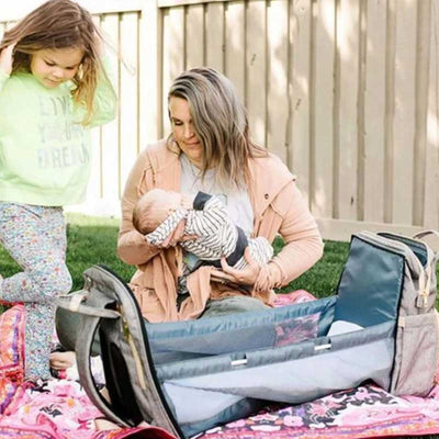 Une maman couche son bébé dans son sac a langer transformable en lit couffin